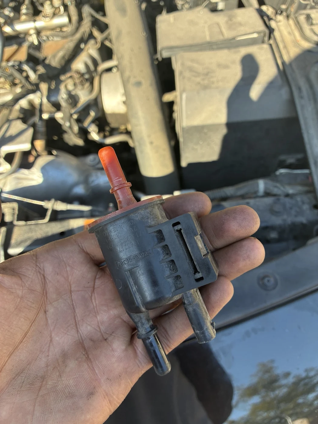Automotive component held beside an engine bay