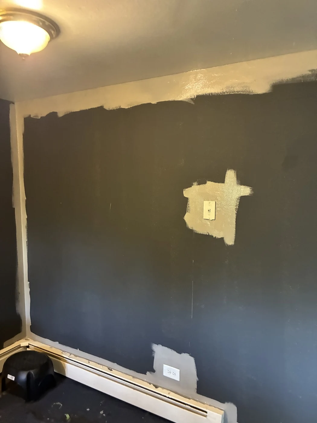 Wall showing paint along the ceiling edge, corners, switch, and outlet.