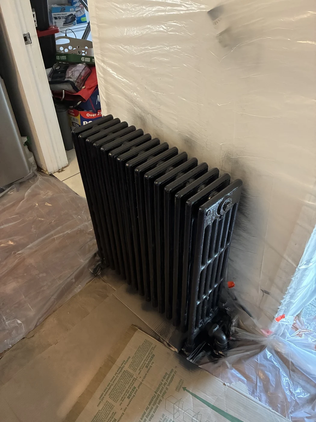 Black radiator surrounded by protective plastic and cardboard.